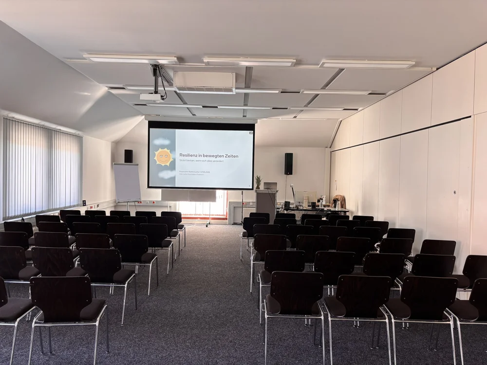 Vortragssaal im Finanzamt Wolfenbüttel mit Bestuhlung und Leinwand: „Resilienz in bewegten Zeiten“